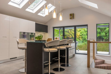 This is an example of a modern eat-in kitchen in Cheshire with flat-panel cabinets, white cabinets and with island.