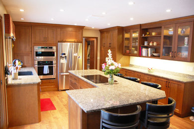 Example of a mid-sized classic u-shaped light wood floor open concept kitchen design in Other with an undermount sink, shaker cabinets, medium tone wood cabinets, granite countertops, white backsplash, stainless steel appliances and an island