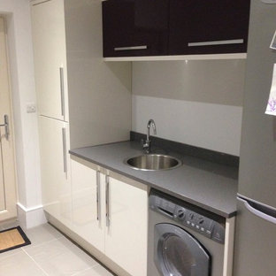 Small contemporary kitchen pantry photos - Example of a small trendy galley ceramic floor kitchen pantry design in Cambridgeshire with a drop-in sink, flat-panel cabinets, beige cabinets, quartzite countertops and stainless steel appliances