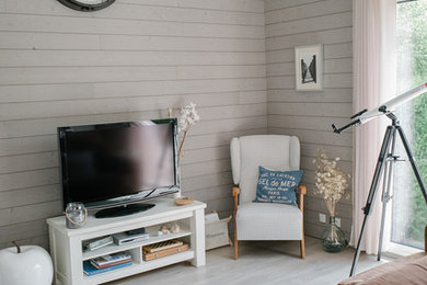 Cette photo montre un salon mansardé ou avec mezzanine bord de mer de taille moyenne avec une bibliothèque ou un coin lecture, un mur beige, parquet clair, aucune cheminée, un téléviseur indépendant et un sol beige.