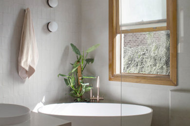 This is an example of a mid-sized contemporary bathroom in Sydney with flat-panel cabinets, medium wood cabinets, a freestanding tub, an open shower, a one-piece toilet, beige tile, porcelain tile, beige walls, terrazzo floors, a drop-in sink, engineered quartz benchtops, grey floor, an open shower, white benchtops, a single vanity and a floating vanity.