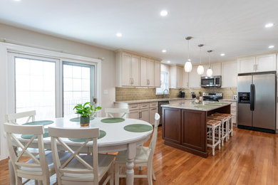 Mid-sized elegant l-shaped medium tone wood floor and brown floor eat-in kitchen photo in Philadelphia with an undermount sink, shaker cabinets, white cabinets, quartzite countertops, brown backsplash, subway tile backsplash, stainless steel appliances, an island and beige countertops