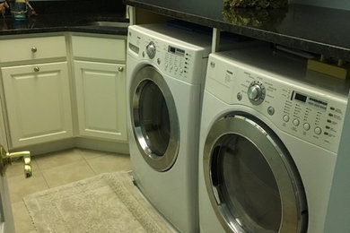 Inspiration for a mid-sized transitional l-shaped porcelain tile and beige floor dedicated laundry room remodel in Baltimore with white cabinets, an undermount sink, raised-panel cabinets, blue walls, a side-by-side washer/dryer and black countertops