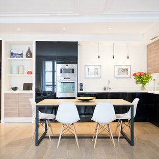 Inspiration pour une salle à manger ouverte sur la cuisine design de taille moyenne avec un mur blanc et un sol en bois brun.