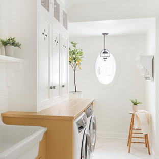 ミネアポリスの中サイズのカントリー風おしゃれな家事室 (ドロップインシンク、インセット扉のキャビネット、黄色いキャビネット、左右配置の洗濯機・乾燥機、白い床、黄色いキッチンカウンター) の写真