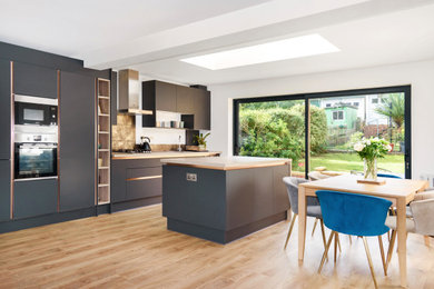 Photo of a medium sized contemporary single-wall open plan kitchen in London with grey cabinets, wood worktops, metallic splashback, porcelain splashback, integrated appliances, an island and brown worktops.