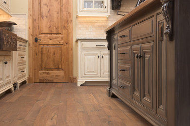 Large mountain style u-shaped medium tone wood floor open concept kitchen photo in Other with a farmhouse sink, beaded inset cabinets, gray cabinets, wood countertops, white backsplash, stone tile backsplash, stainless steel appliances and an island