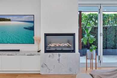 Photo of a mid-sized modern open concept living room in Sydney with white walls, medium hardwood floors, a standard fireplace, a stone fireplace surround and a wall-mounted tv.