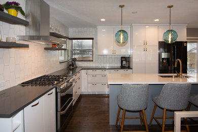Inspiration for a contemporary l-shaped medium tone wood floor and brown floor open concept kitchen remodel in Minneapolis with a single-bowl sink, flat-panel cabinets, white cabinets, quartz countertops, white backsplash, porcelain backsplash, stainless steel appliances, an island and gray countertops