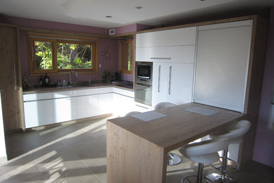 Foto på ett mellanstort funkis kök, med en undermonterad diskho, släta luckor, vita skåp, träbänkskiva, stänkskydd med metallisk yta, rostfria vitvaror, en halv köksö och grått golv