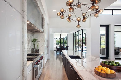 Inspiration for a large transitional galley porcelain tile open concept kitchen remodel in Austin with a double-bowl sink, flat-panel cabinets, white cabinets, marble countertops, multicolored backsplash, stone slab backsplash, stainless steel appliances and an island