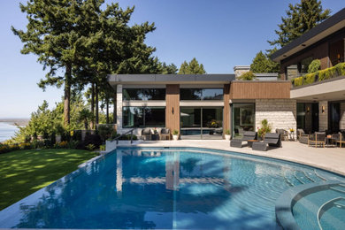 Pool - large modern backyard custom-shaped infinity pool idea in Vancouver with decking