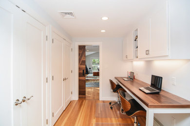 Mid-sized trendy built-in desk medium tone wood floor and brown floor home office photo in Boston with white walls