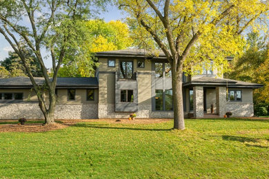 This is an example of a large contemporary two-storey beige exterior in Minneapolis with stone veneer and a flat roof.