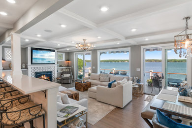 Example of a large trendy open concept light wood floor, beige floor and coffered ceiling living room design in Milwaukee with a bar, gray walls, a standard fireplace, a tile fireplace and a wall-mounted tv