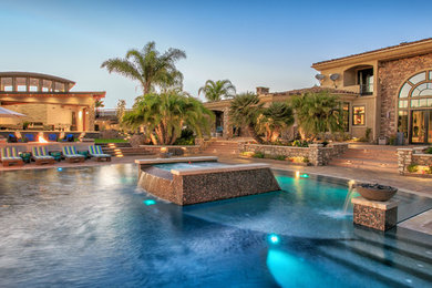 Large modern backyard custom-shaped pool in San Diego with a pool house and concrete pavers.