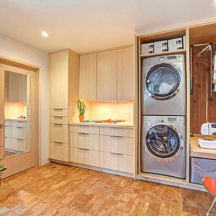オレンジカウンティのコンテンポラリースタイルのおしゃれな家事室 (フラットパネル扉のキャビネット、淡色木目調キャビネット、グレーの壁、目隠し付き洗濯機・乾燥機、コルクフローリング) の写真