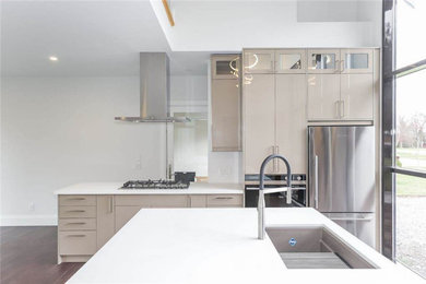 This is an example of a medium sized contemporary l-shaped kitchen/diner in Toronto with a submerged sink, flat-panel cabinets, beige cabinets, engineered stone countertops, stainless steel appliances, dark hardwood flooring, an island, brown floors and white worktops.