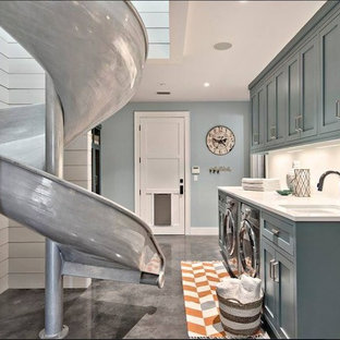 Diseño de lavadero actual con armarios con paneles empotrados, puertas de armario turquesas, suelo de cemento, lavadora y secadora juntas y suelo gris