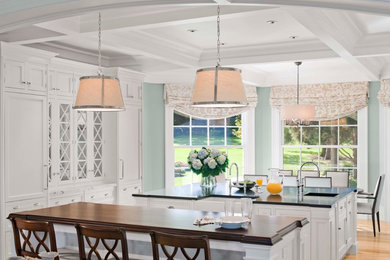 Open concept kitchen - large transitional light wood floor and beige floor open concept kitchen idea in Miami with a farmhouse sink, recessed-panel cabinets, white cabinets, solid surface countertops, stainless steel appliances, two islands and black countertops