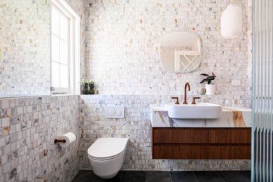Mid-sized midcentury bathroom in Sydney with medium wood cabinets, an open shower, a wall-mount toilet, white tile, mosaic tile, white walls, porcelain floors, an integrated sink, engineered quartz benchtops, grey floor, an open shower, white benchtops, a single vanity and a floating vanity.