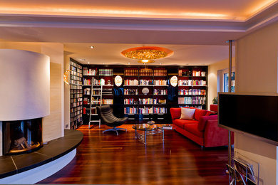 This is an example of a large contemporary open concept living room in Nuremberg with a library, white walls, dark hardwood floors, a wood stove, a plaster fireplace surround, no tv and brown floor.
