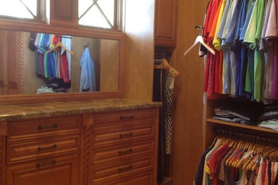 Walk-in closet - mid-sized traditional gender-neutral ceramic tile walk-in closet idea in Miami with raised-panel cabinets and medium tone wood cabinets