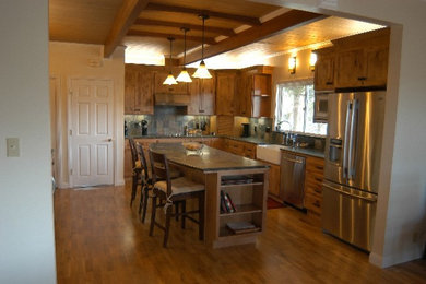 Example of a large classic l-shaped medium tone wood floor eat-in kitchen design in San Francisco with a farmhouse sink, flat-panel cabinets, distressed cabinets, limestone countertops, multicolored backsplash, stone tile backsplash, stainless steel appliances and an island