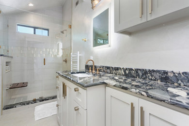 Mid-sized contemporary bathroom in Austin with recessed-panel cabinets, grey cabinets, an alcove shower, white tile, porcelain tile, white walls, an undermount sink, a hinged shower door, black benchtops, a single vanity and a built-in vanity.