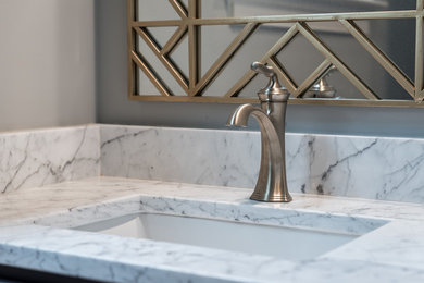 Powder room - transitional powder room idea in Raleigh with a two-piece toilet, gray walls, an undermount sink, marble countertops and white countertops