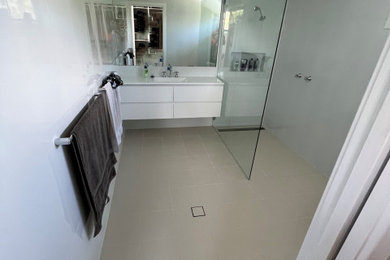 Large contemporary master bathroom in Sydney with beaded inset cabinets, white cabinets, an open shower, a one-piece toilet, white tile, ceramic tile, white walls, ceramic floors, a drop-in sink, limestone benchtops, beige floor, an open shower, white benchtops, a niche, a single vanity and a floating vanity.