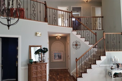 Large tuscan wooden curved staircase photo in Charlotte with painted risers