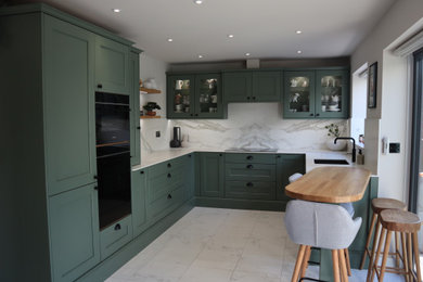 Design ideas for a medium sized traditional u-shaped kitchen/diner in Hampshire with a single-bowl sink, shaker cabinets, green cabinets, engineered stone countertops, engineered quartz splashback, black appliances, ceramic flooring, no island, white floors and white worktops.