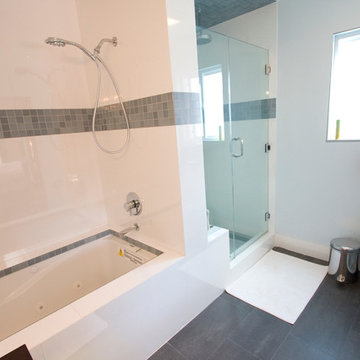 Deep Soaking Tub With Dark Tile Band and Glass Shower