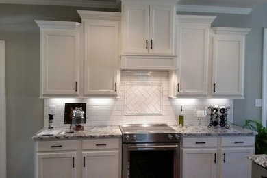 アトランタにある広いモダンスタイルのおしゃれなアイランドキッチン (ダブルシンク、シェーカースタイル扉のキャビネット、白いキャビネット、大理石カウンター、白いキッチンパネル、セラミックタイルのキッチンパネル、シルバーの調理設備、淡色無垢フローリング) の写真