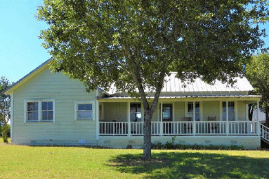Example of a large farmhouse yellow one-story wood exterior home design in Houston with a metal roof