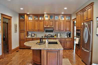 This is an example of a mid-sized traditional l-shaped eat-in kitchen in Other with an undermount sink, raised-panel cabinets, medium wood cabinets, quartz benchtops, stainless steel appliances and with island.