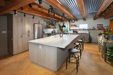 Photo of a large industrial l-shaped eat-in kitchen in Los Angeles with a double-bowl sink, flat-panel cabinets, distressed cabinets, quartz benchtops, white splashback, subway tile splashback, stainless steel appliances, concrete floors and with island.