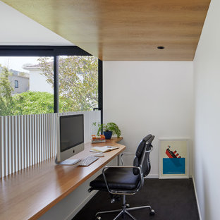 Inspiration for a small contemporary home office in Melbourne with white walls, carpet, a built-in desk and black floor.