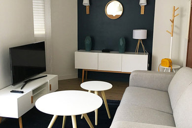 Idée de décoration pour un salon nordique de taille moyenne et ouvert avec un mur bleu, parquet clair, un téléviseur indépendant et un sol beige.