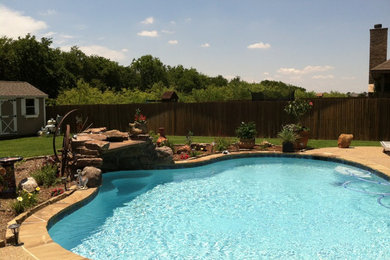 Photo of a mid-sized traditional backyard custom-shaped natural pool in Dallas with a water feature and concrete pavers.