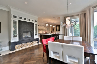 Photo of a mid-sized contemporary open plan dining in Toronto with white walls, dark hardwood floors, a standard fireplace, a tile fireplace surround and brown floor.