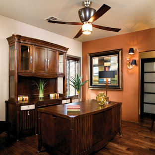 Design ideas for a modern study in Orange County with orange walls, dark hardwood flooring, a freestanding desk and brown floors.