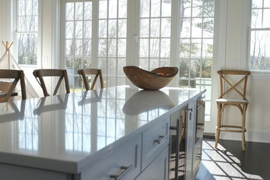Inspiration for a mid-sized coastal dark wood floor and brown floor kitchen remodel in New York with recessed-panel cabinets, white cabinets, marble countertops, stainless steel appliances, an island and white countertops