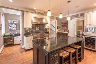 Inspiration for a medium tone wood floor kitchen remodel in Other with a farmhouse sink, raised-panel cabinets, white cabinets, granite countertops, gray backsplash, metal backsplash, stainless steel appliances and an island