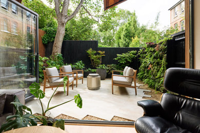 Design ideas for a small modern back partial sun garden for summer in London with natural stone paving and a wood fence.