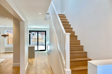 Diseño de escalera en U actual con escalones de madera, contrahuellas de madera y barandilla de madera
