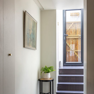 Design ideas for a medium sized bohemian look-out basement in London with pink walls, concrete flooring, no fireplace, a plastered fireplace surround and grey floors.