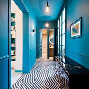 Exempel på en mellanstor eklektisk hall, med blå väggar, en dubbeldörr, svart golv och klinkergolv i keramik