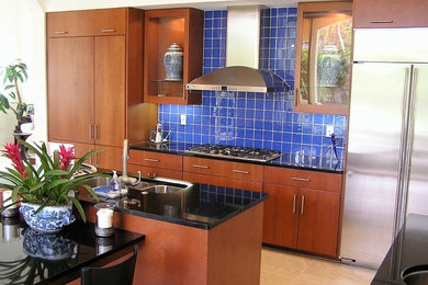 Photo of a mid-sized modern galley open plan kitchen in Miami with an undermount sink, flat-panel cabinets, brown cabinets, granite benchtops, blue splashback, porcelain splashback, stainless steel appliances, limestone floors, with island and beige floor.